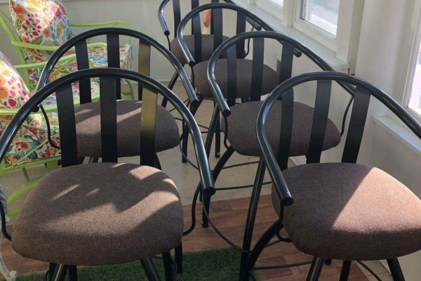 A set of six black dining chairs with tan seat cushions.