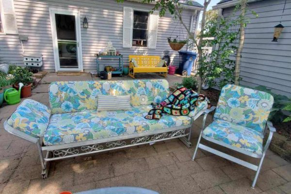 A colorful blue paisley backyard couch and matching chair on a patio.