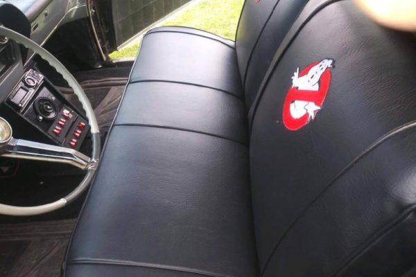 Upholstered black vehicle seats with a Ghostbusters logo.